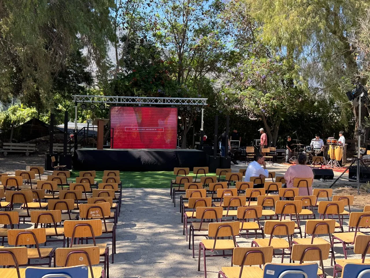 Montaje exterior con pantalla, sillas y área para público